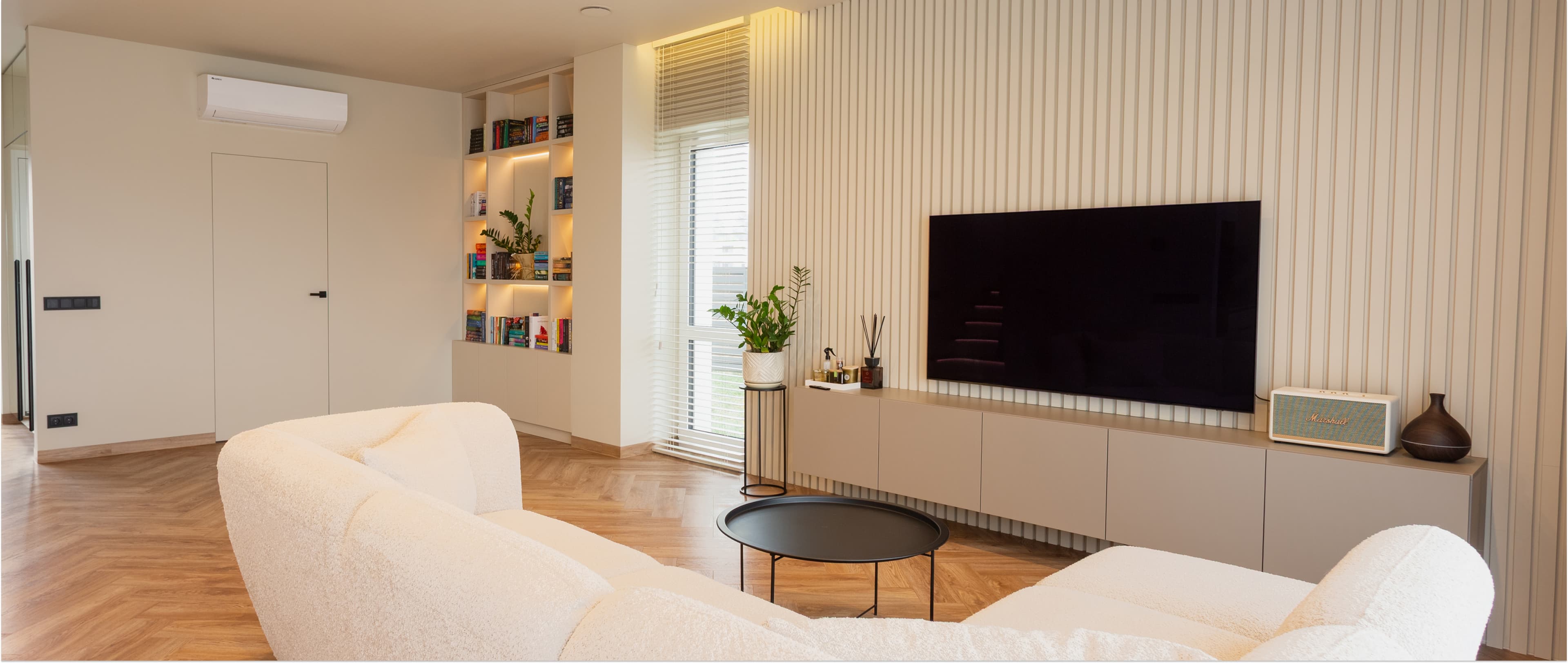 Moderni svetainė po vidaus apdailos su baltais minkštais fotelilais ir medine TV siena